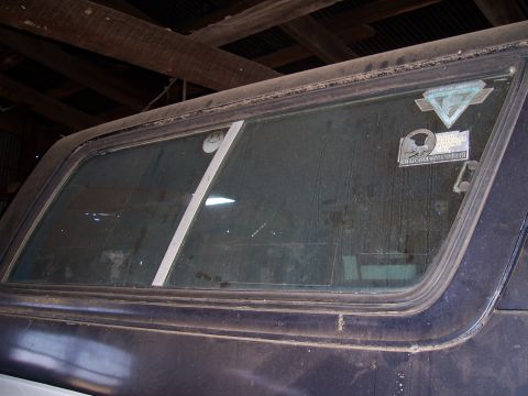 1983 Ford Bronco - A close-up of the rear window of an SUV, showing various stickers and a hint of the interior.