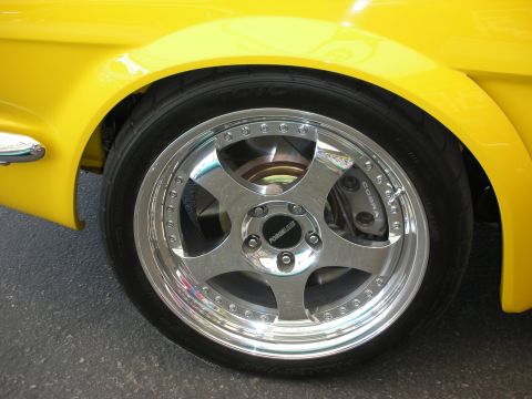 1998 Ford Crown Victoria - polished chrome five-spoke wheel wrapped in a Toyo tire sits under the yellow fender of a custom car.
