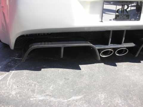 1998 Ford Crown Victoria - Close-up of a silver car's carbon-fiber rear diffuser and dual round exhaust tips below a duPont Registry license plate.