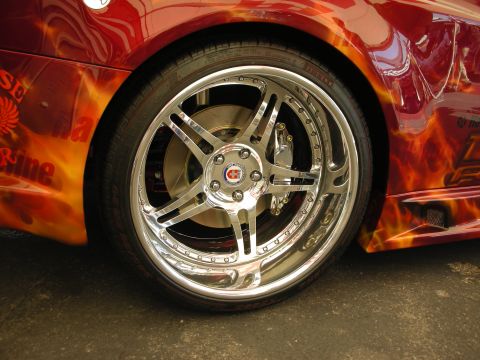 1998 Ford Crown Victoria - polished five-spoke wheel and low-profile tire fill the wheel well of a car painted with orange flame airbrush graphics.