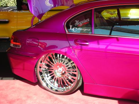 1998 Ford Crown Victoria - Rear quarter of a pink BMW sedan slammed on a multi-spoke chrome wheel, side glass carrying Meguiar's and designs decals.