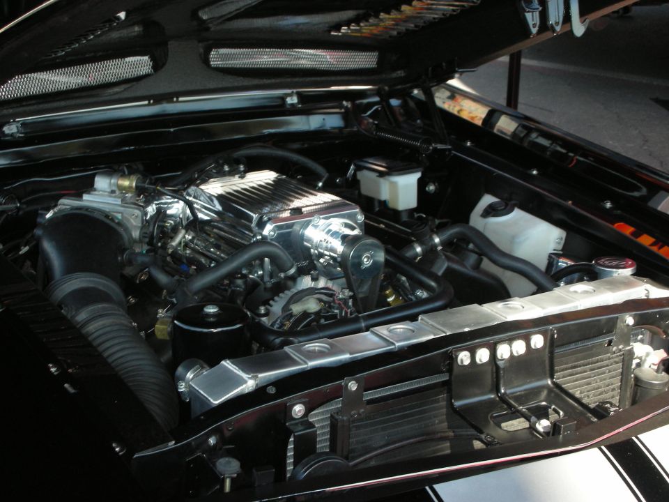 Open engine bay showing supercharged V8 with chrome intake and polished components