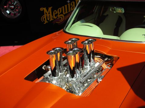 1998 Ford Crown Victoria - Five chrome velocity stacks rise through an opening in the orange hood of a custom car with a light green interior.