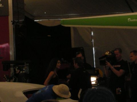 1998 Ford Crown Victoria - In a dim tent, a dark-haired woman stands near crew members and a camera operator under a green inflatable arch.