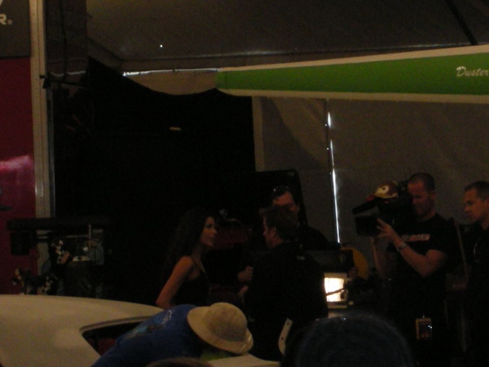 Dimly lit interview scene with a woman and a camera operator under a tent