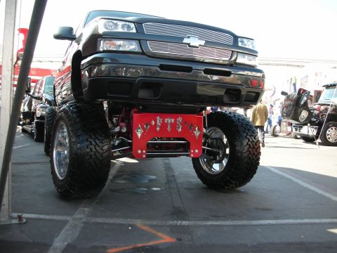 1998 Ford Crown Victoria - lifted black Chevrolet pickup sits high on large off-road tires with a billet grille, viewed head-on at an outdoor show.