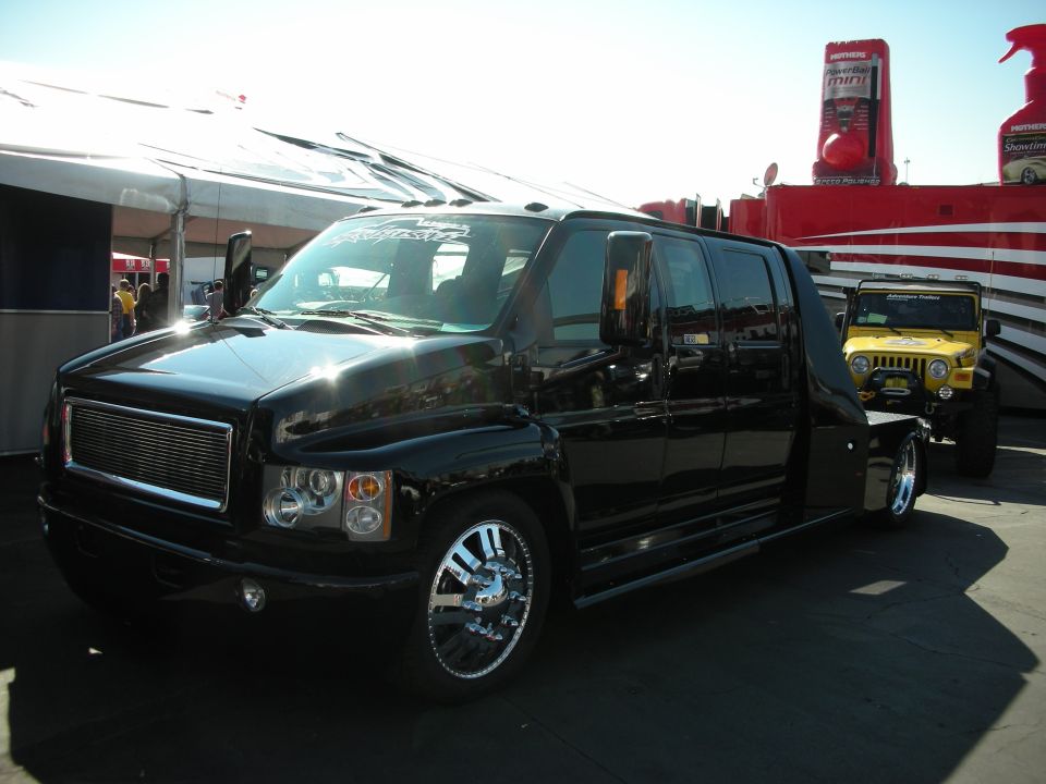 Black custom medium-duty crew cab hauler truck on chrome wheels at a show