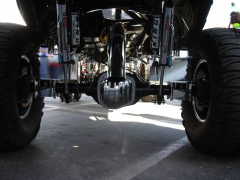 1998 Ford Crown Victoria - Looking under a lifted truck, the rear differential and chrome King coil-over shocks sit between large off-road tires.