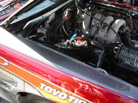 1998 Ford Crown Victoria - engine bay viewed over a red fender that reads TOYO TIRES, showing the intake manifold and fuse box.
