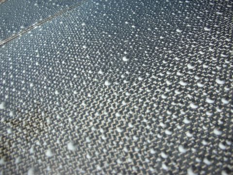 1998 Ford Crown Victoria - Macro shot of a carbon-fiber weave surface beaded with water droplets.