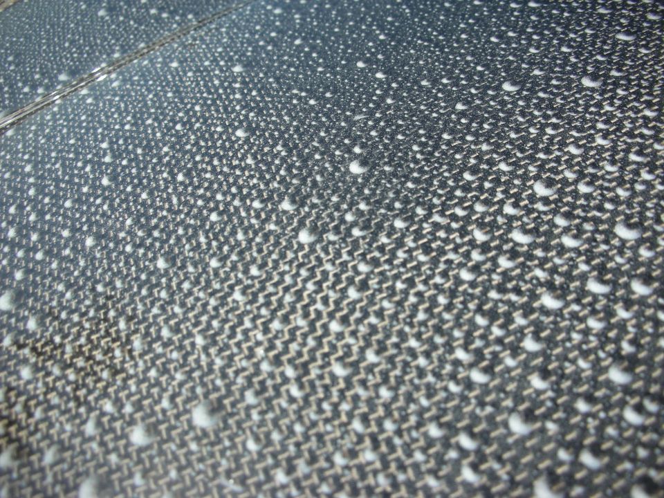 Close-up of carbon-fiber weave panel covered in water droplets