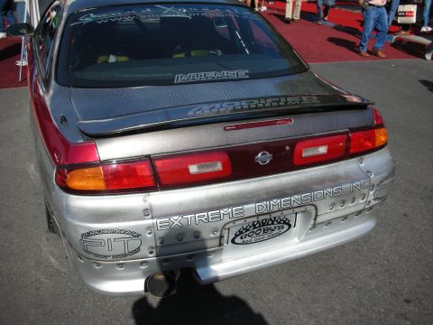 1998 Ford Crown Victoria - Rear of a two-tone Nissan coupe with a wide-body kit lettered EXTREME DIMENSIONS at a show.