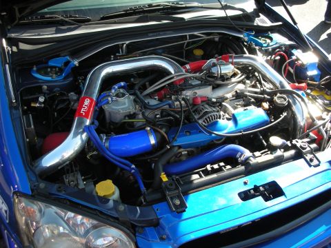 1998 Ford Crown Victoria - engine bay of a blue car showing a boxer engine with blue silicone hoses and a polished intake.