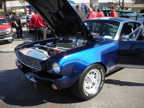 1998 Ford Crown Victoria - blue classic Mustang fastback with white stripes and hood raised parked at a car show.
