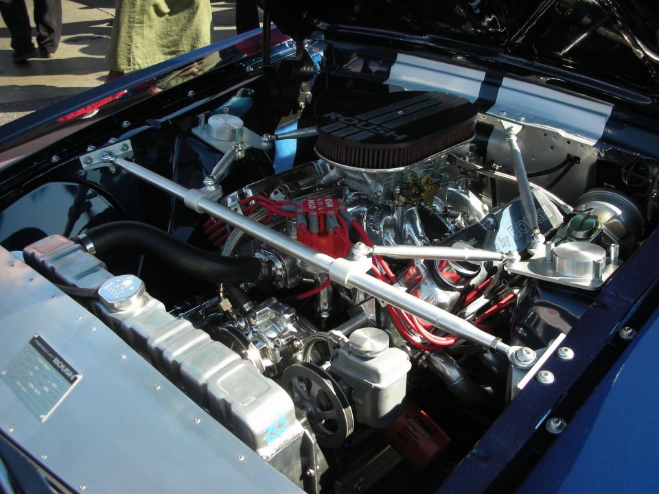 V8 engine with chrome air cleaner and red plug wires in a blue engine bay