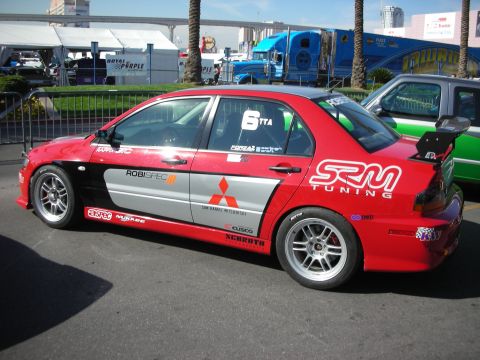 1998 Ford Crown Victoria - red-and-silver Mitsubishi Lancer Evo race car with SRM Tuning livery parked outdoors.