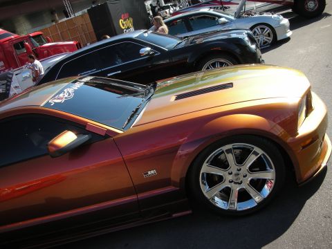 1998 Ford Crown Victoria - copper-orange late-model Mustang on chrome wheels lines up among other show cars.