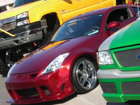 1998 Ford Crown Victoria - Front of a maroon Nissan 350Z with chrome wheels parked beside a green and a yellow truck.