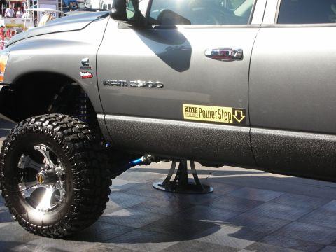 1998 Ford Crown Victoria - Side profile of a lifted gray Dodge Ram 2500 Cummins diesel truck with chrome wheels and an AMP PowerStep decal, raised on a stand.