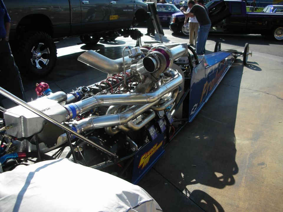 Chrome turbocharged engine on a long blue dragster rail car
