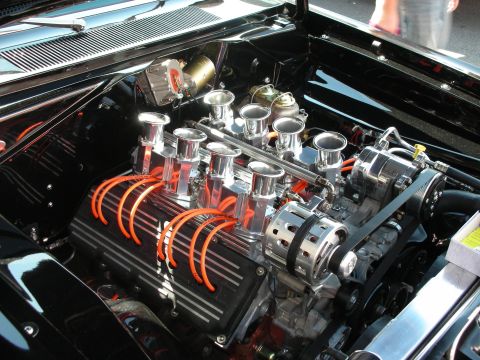 1998 Ford Crown Victoria - Engine bay close-up of a black-crinkle V8 with chrome velocity-stack fuel injection and orange spark plug wires.
