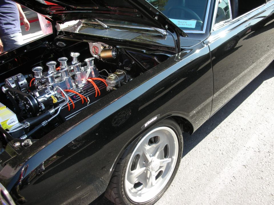 Black classic car with open hood showing chrome carbureted V8 engine