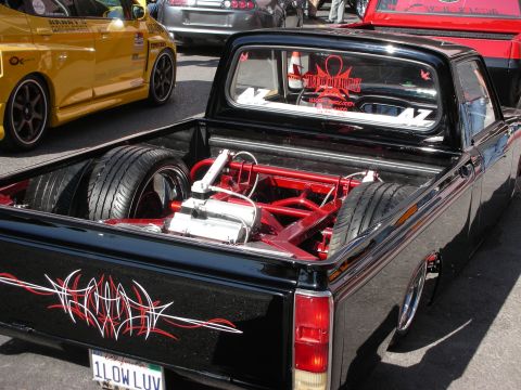 1998 Ford Crown Victoria - lowered black mini pickup with pinstriping and a chrome engine mounted in the bed, plate reading 1LOWLUV.