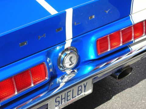 1998 Ford Crown Victoria - Rear detail of a blue Shelby Mustang with white stripes, Shelby badging, cobra-emblem fuel cap and a SHELBY license plate.