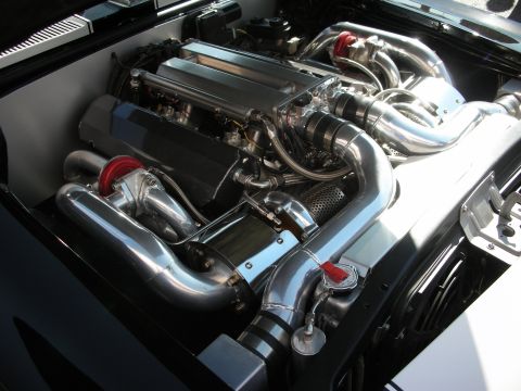 1998 Ford Crown Victoria - polished inline engine sits in a black bay surrounded by chrome intercooler tubing and bright red silicone couplers.