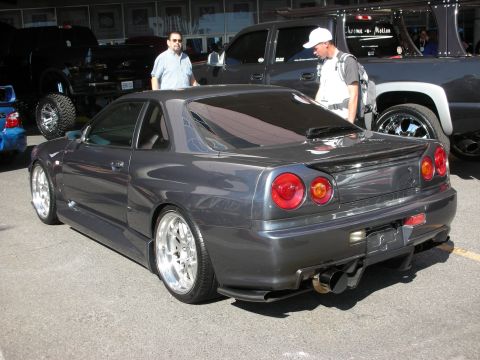 1998 Ford Crown Victoria - grey Nissan Skyline coupe shows its signature round taillights and rear diffuser among other cars at an event.
