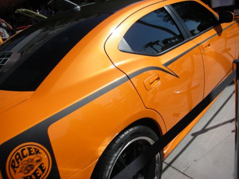 1998 Ford Crown Victoria - orange sedan shows glossy paint, black side stripes and a bee-themed Racer decal on its rear quarter panel.