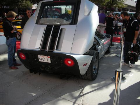 1998 Ford Crown Victoria - silver Ford GT shows its twin stripes, round taillights and a GT40 TT license plate at a crowded show.