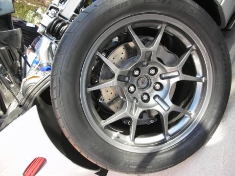 1998 Ford Crown Victoria - multi-spoke alloy wheel wraps a drilled and slotted brake rotor on a Pirelli P Zero tire of a silver sports car.