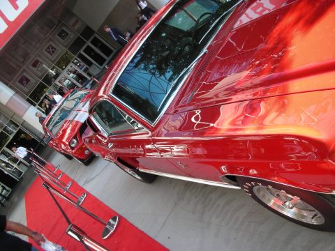 1998 Ford Crown Victoria - highly polished red classic muscle car sits in profile on red carpet, reflecting the show surroundings.