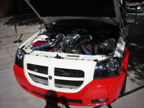 1998 Ford Crown Victoria - red Dodge with its hood open reveals a built engine with polished supercharger and blue and white intake piping.