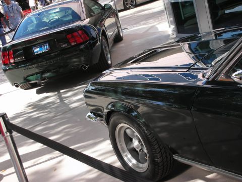 1998 Ford Crown Victoria - rear of a green Mustang sedan sits beside a dark green classic fastback's rear quarter and wheel at a show.