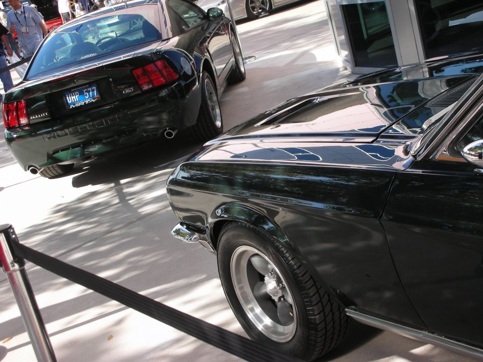 Rear of green Mustang beside a dark green fastback at an outdoor show