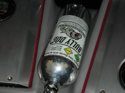 1998 Ford Crown Victoria - polished 'Bully Dog' nitrous oxide system bottle mounted in a gray and red carpeted trunk.