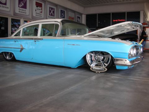 1998 Ford Crown Victoria - light blue lowered classic four-door sedan with its hood open sits on a polished floor inside a showroom.