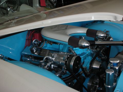 1998 Ford Crown Victoria - detailed turquoise engine bay with twin chrome velocity-stack air cleaners and polished pulleys under a white hood.