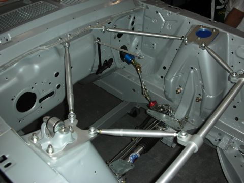 1998 Ford Crown Victoria - Empty gray-primered engine bay fitted with tubular control arms, adjustable links and a rack-and-pinion steering assembly.