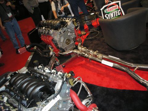 1998 Ford Crown Victoria - Two intake-manifold V8 engines and a polished stainless dual exhaust laid out on red carpet at a Castrol Syntec display.