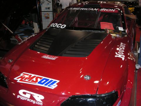 1998 Ford Crown Victoria - Front view of a red road-race car's vented hood and windshield banner reading American Iron, with Amsoil and Griggs Racing decals.
