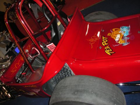 1998 Ford Crown Victoria - Rear deck of a red hot rod airbrushed with a cartoon Tea Pot character and gold pinstriping above a wide slick tire.