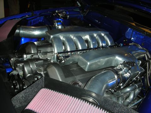 1998 Ford Crown Victoria - Close-up of a polished aluminum V8 intake manifold and piping in a blue engine bay with a red cone air filter in front.
