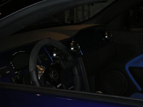 1998 Ford Crown Victoria - Dimly lit interior of a blue car showing a flat-bottom suede steering wheel, digital dash and blue trim lighting.
