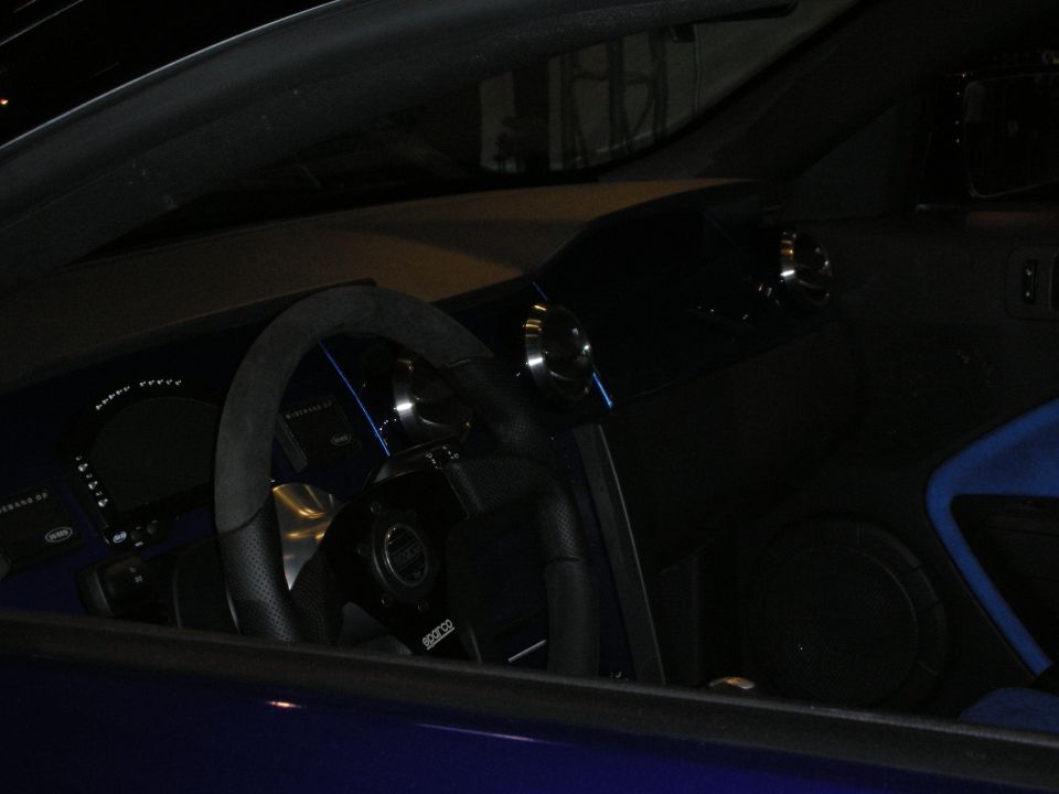 Dark interior of a blue car with suede steering wheel and digital gauges