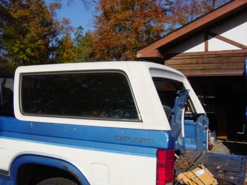 1991 Ford Bronco - The rear section of a two-tone Ford Explorer Sport Trac is visible, a white camper shell over the bed.
