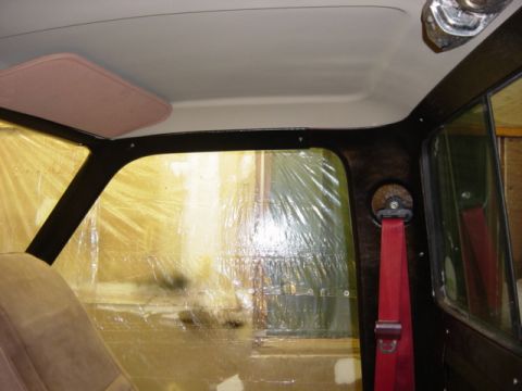 1991 Ford Bronco - Interior view of a vehicle, with plastic sheeting covering the windows and a red seatbelt visible.