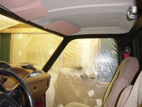 1991 Ford Bronco - The interior of a vehicle is shown, with plastic sheeting covering the windows and the dashboard undergoing work.